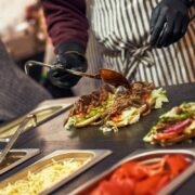 A chef preparing a sandwich with fresh salad. Food cort of street fair. Kitchen outdoors